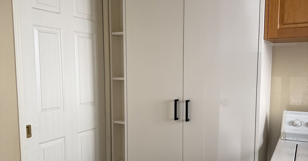 Custom mudroom storage closet with doors closed in a Calgary entryway, beside a narrow built-in shelving unit